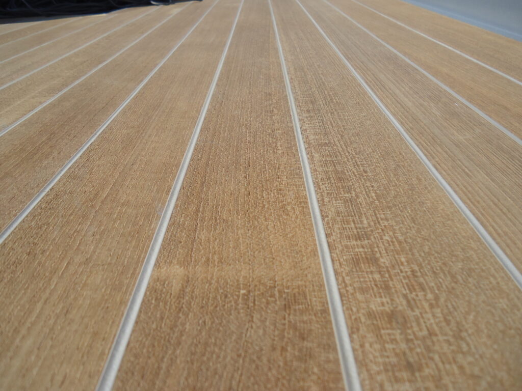 Closeup of teak decking gray seams that are underfilled below the surface of the teak